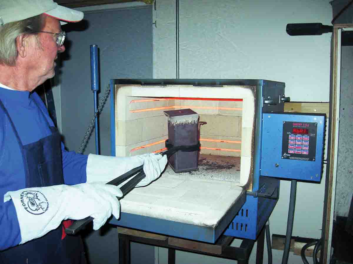 Al Springer is placing a crucible in a furnace for color case hardening.